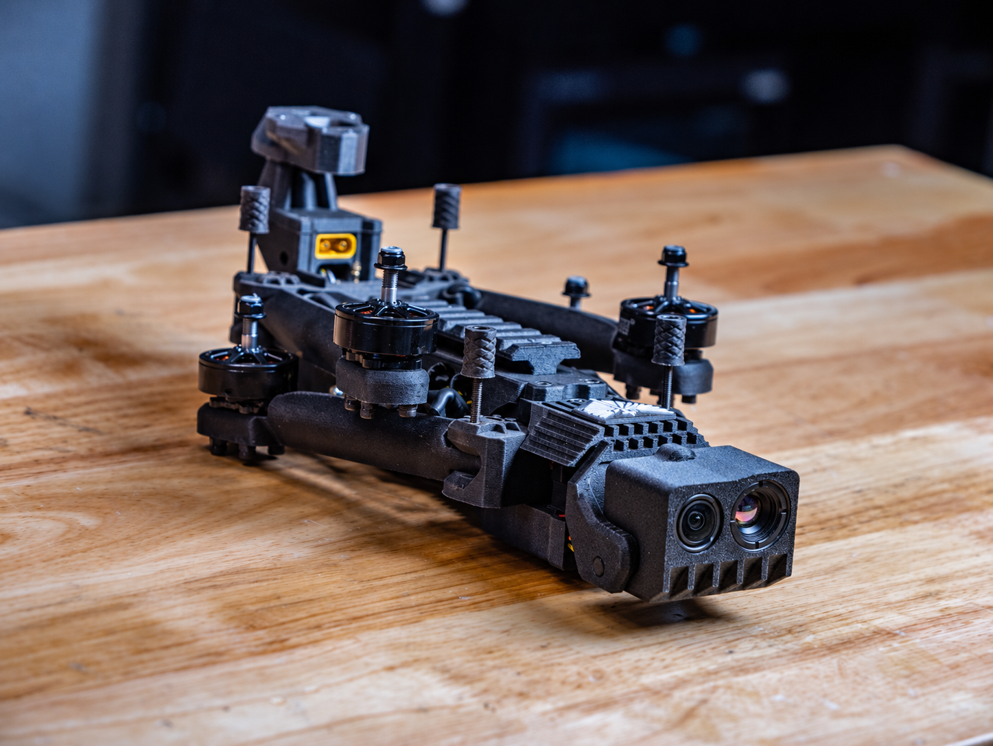 Sentinel Dynamics Picket-7 on a workbench, arms folded, with the dual EO and thermal camera payload facing forward